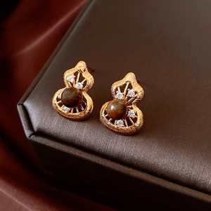 Detailed close-up of golden gourd stud earrings with tiger eye stone and zircons