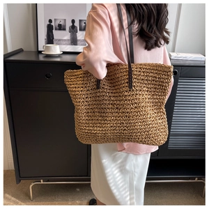 Detailed back view of a woven straw tote bag worn by a model in a modern interior