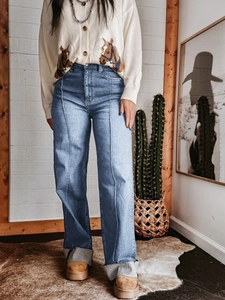 Detail van high-waisted jeans met wijde pijpen, verticale naad en onafgewerkte zoom