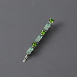 Detail of silver hair clip featuring round green and rectangular light green crystals
