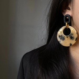 Detail view of leopard print resin earrings on model with black matte studs