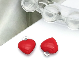 Macro shot of two polished red enamel heart pendants with silver metal edges for DIY jewelry