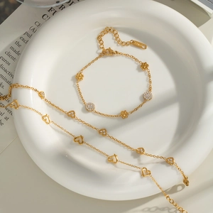 Detailed shot of 18K gold titanium steel bracelets with floral and heart charms on a tray
