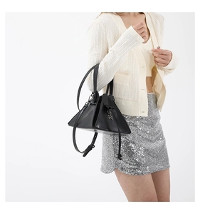 Detail of black punk-style triangle crossbody bag with silver bear pendant on model