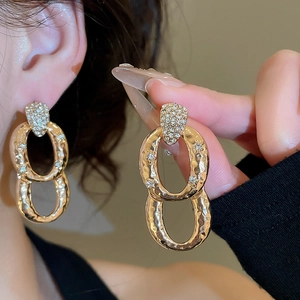 Detail view of gold oval drop earrings with white zircon on a model for luxury style