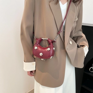 Chic burgundy mini leather shoulder bag with silver bead trim on a fashion model