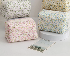 Quilted floral makeup bags in purple and blue shades displayed on geometric stands