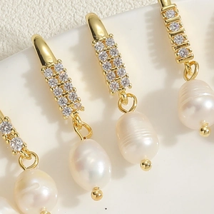Detailed macro view of baroque freshwater pearl earrings with zircon studded gold hooks