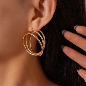 Close-up of model wearing triple-layered gold hollow round twisted hoop earrings