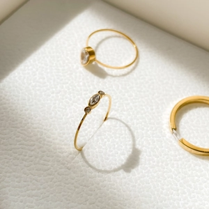 Detailed macro view of gold-plated rings with zircon clover pattern on white leather