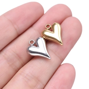304 stainless steel heart pendants in gold and silver finish shown on a fingertip