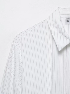 Close-up of fine black vertical stripes on a white cotton shirt with detailed neckline stitching