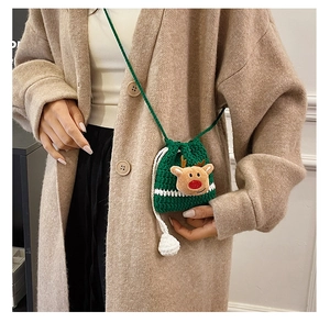 Detail of hand-knitted green crossbody bag with cute reindeer doll decor for Christmas