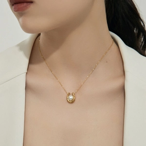 Collier en acier titane en forme de U avec perle centrale sur un pendentif fer à cheval doré