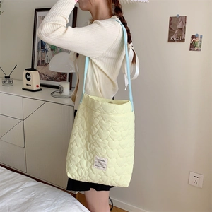 Detail of heart-shaped quilted canvas bag with contrast blue strap and woven label