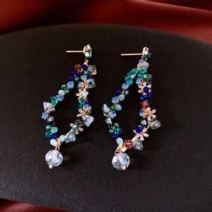 Close-up of handmade geometric beaded earrings with colorful crystals and gold metal hooks