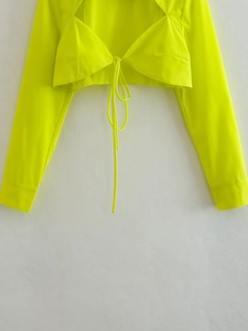 Détail d'un haut court à manches longues vert fluo avec lacets et design ajouré tendance