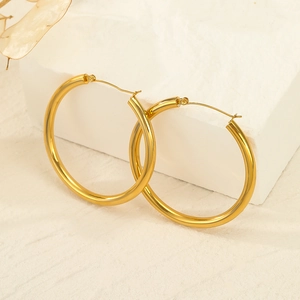 Elegant large gold hoop earrings in polished stainless steel on a natural stone display