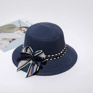 Detailed view of a navy blue straw cloche hat with a striped bow and pearl accent
