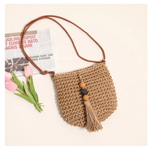 Detail of woven straw crossbody bag with decorative wooden beads and fringe tassel
