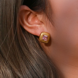 Detail of vintage square pink zircon stud earring with golden spiral texture on model