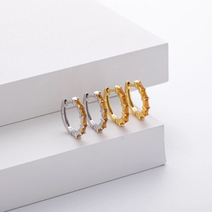 Detail view of gold and silver S925 sterling silver hoop earrings with amber zircon