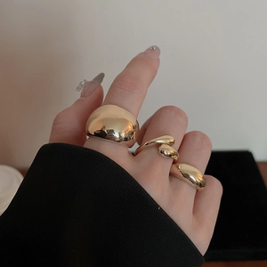 Close-up of three irregular golden liquid-metal style rings worn on fingers