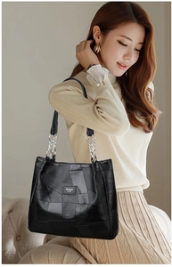 Close-up of black PU leather tote bag featuring metal chain and professional stitching