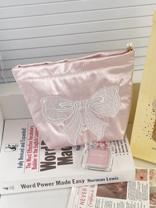 Pink satin cosmetic bag with large white embroidered bow and pearl zipper pull handle