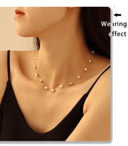 Détail du collier avec chaîne dorée, perles blanches et pierres de marbre texturées