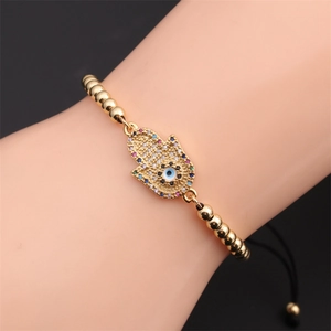 Detail of gold Hamsa hand bracelet with zircon evil eye and adjustable black cord