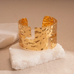 Macro view of gold cuff bracelet featuring hammered texture and geometric cutouts