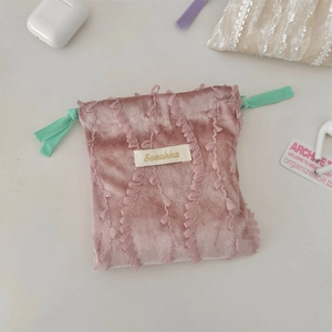 Detailed view of pink velvet drawstring pouch with lace trim and contrasting green cord
