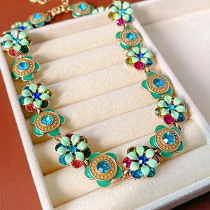 Detail of vintage flower necklace with green enamel and colored crystals in a jewelry box