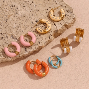 Detailed macro view of colorful enamel 18K gold plated donut hoop earrings on stone