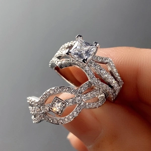 Detail of silver engagement ring set with princess cut zircon and crisscross micro-pave band