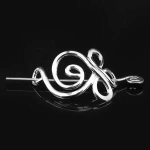 Silver Viking hair pin with spiral Celtic design on reflective black background