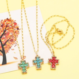 Detail of cross pendant with colorful cubic zirconia on a golden Figaro chain