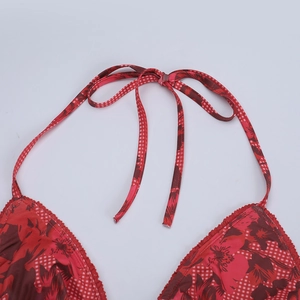 Détail d'un haut de bikini floral rouge avec bretelles à carreaux et nœud au cou