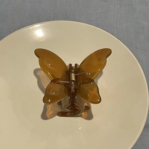 Macro shot of an amber butterfly hair claw clip with translucent finish on a white plate