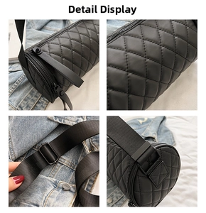 Detail view of black quilted cylinder bag showing zipper, strap buckle, and texture