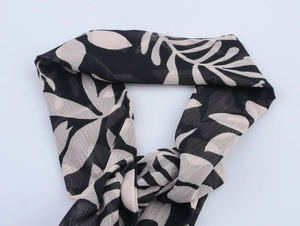 Detail of leaf print chiffon scarf with ruffles and soft texture in black and beige