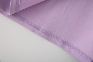 Makroaufnahme von lila Strickstoff mit hochwertigen Saumnähten und feiner Textur