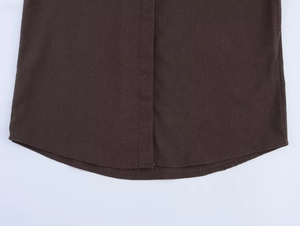 Close-up of linen shirt placket and curved hem showing detailed stitching in dark brown