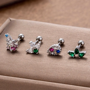 Macro shot of silver stainless steel earrings with colorful zircon butterfly and clover motifs