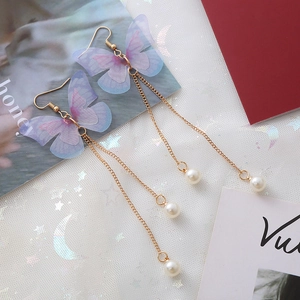 Détails de boucles d'oreilles papillon avec perles et tulle violet sur de la dentelle blanche
