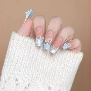 Faux ongles longs carrés bleus style français avec nœud 3D et dentelle sur main