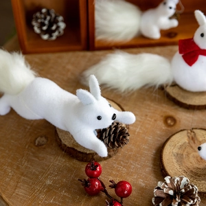 White faux fur squirrel figurines for Christmas tree decor on warm wooden surface