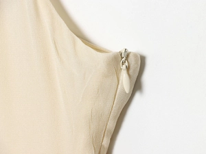 Close-up of the invisible zipper detail on an ivory midi dress with crepe texture