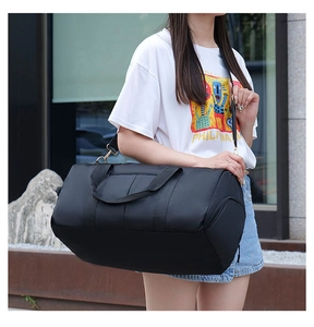 Detailed view of a black fitness bag with gold hardware worn by a model in outdoor setting